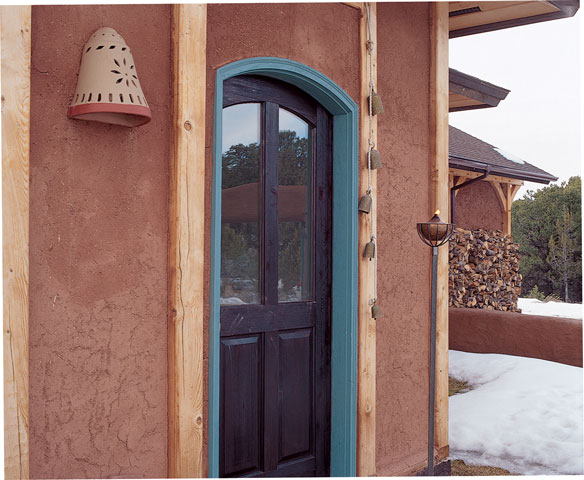 
Guests are greeted with an old terra cotta “doorbell” and glowing oil lamp at the threshold. A straw-clay coating on the foyer’s exterior provides texture, insulation, and soundproofing.
